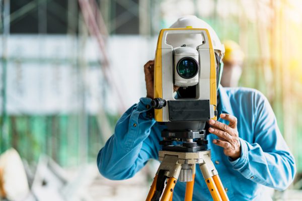 engineer site survey with laser tripod machine in site construction background